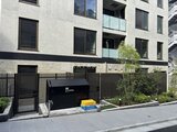 エクサム赤坂 黒いフェンスと緑に囲まれたモダンな建物外観