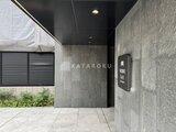 ウィーブベース上野ノース モダンな石張りのエントランスと植栽が配置された建物入口