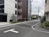 ジェノヴィア竹ノ塚 建物入口前の道路から見た、モダンな外観と周辺環境