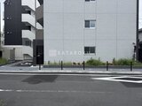 ジェノヴィア竹ノ塚 前面道路から見たモダンな建物外観と駐車場入口