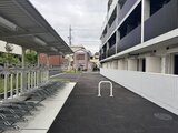 ジェノヴィア竹ノ塚 駐輪スペースと駐車場を備えた開放的な共用通路