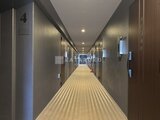 ジェノヴィア竹ノ塚 落ち着いた照明の共用廊下、整然と並ぶ住戸ドアの様子