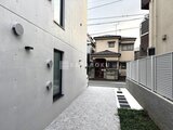 グランパセオ三宿2 白壁の新築住宅と隣地の家並みを見通す駐車スペース