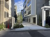 ヴィスタコート幡ヶ谷 モダンな建物に囲まれた、明るい印象のアプローチ通路