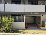ラヴィエール住吉駅前 駐車場入口と緑の植栽がある建物の1階外観