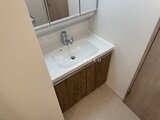 ラヴィエール住吉駅前 白い洗面ボウルと木目調の洗面化粧台、上部に鏡を備えた洗面室
