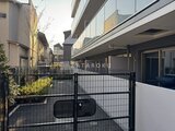 エスグランデ大森 黒いフェンスと白壁で囲まれた開放的な駐車スペース