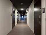 エスグランデ大森 白い壁と黒いドアが並ぶ廊下の奥に光が見える共用通路