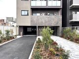 アルコバレーノ南千住 緑化スペースとガレージ入口を備えた現代的な建物外観