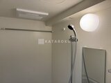 アルコバレーノ南千住 白いタイル張りの浴室、丸型照明と黒いシャワーヘッドの浴室