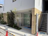 ルミーク大森 木目調パネルと緑の植栽が調和するエントランスの様子