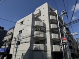 アルコバレーノ亀戸2 青空の下、白いタイル貼りのモダンな4階建てマンション外観