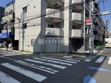 アルコバレーノ亀戸2 交差点角地に立つモダンな外観の建物と前面道路の様子