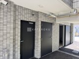 アルコバレーノ亀戸2 タイル貼りの壁に黒いドアが並ぶ共用廊下の様子