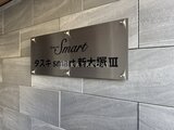 タスキスマート新大塚3 石貼りの壁面に取付けられた物件名表示プレート