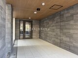 タスキスマート新大塚3 木目調の天井と落ち着いた色合いのタイル張りエントランス