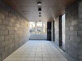 タスキスマート新大塚3 明るい共用部廊下から外部へ続く開放的なエントランス通路