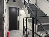 タスキスマート新大塚3 モダンな階段と黒いドアが配置された共用廊下