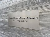 ザ・レジデンス市谷台町 木目調のアクセント壁に取り付けられた物件名プレート