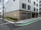 ラヴィエール新板橋 角地に建つモダンな建物の外観と駐車場入口の様子