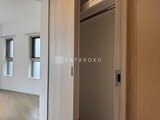 ラヴィエール新板橋 エレベーターホール側から見たモダンな玄関と明るいリビング空間