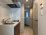 ラヴィエール新板橋 コンパクトで機能的なキッチンと玄関が見える廊下空間