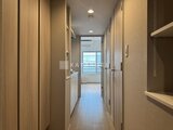 ラヴィエール新板橋 木目調のドアと収納が並ぶ廊下から光が入るリビング方向への眺め