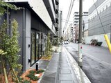 アーバネックス両国レジデンス 建物前面の整備された通路と周辺街並みを見た外観