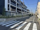ルネサンスコート祐天寺テラス 前面道路から見たモダンな建物外観と横断歩道の様子