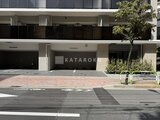 クレストコート王子 前面道路から見たモダンな建物ファサードと駐車場の様子