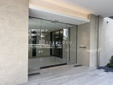 クレストコート王子 モダンな石貼りの壁に囲まれた、大型ガラス戸のエントランス