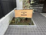 リビオメゾン東陽町ヒュッテ エントランスの木製サイン板と落ち着いた舗装が印象的な建物入口