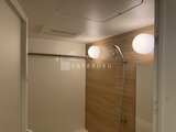 パークアクシス大森山王 木目調のアクセント壁と円形照明がある、モダンな浴室空間