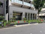 テラス神田猿楽町 緑のフェンスと植栽に囲まれたモダンな建物のエントランス周辺