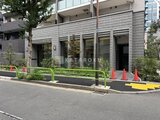 テラス神田猿楽町 落ち着いた石張りの外観と緑の植栽が調和した建物正面