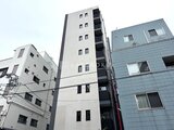 アーバネックス文京千駄木 周辺建物に囲まれた白系の細身マンション外観