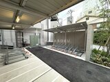 クレストコート東池袋 屋根付きの駐輪スペースと駐車場を備えた開放的な外構の様子