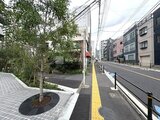クレストコート東池袋 前面道路から見た建物エントランスと周辺の開放的な街並みの様子