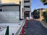 プレジリア代々木参宮橋 モダンな外観の建物とコンクリート舗装のアプローチの様子