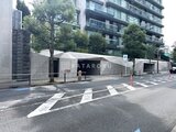 パークマンション檜町公園 建物前の駐車場入口と緑に囲まれた外観
