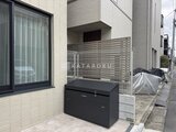 アトリオフラッツ自由が丘イースト 建物側面の物置とメッシュフェンスが設置されたエクステリア空間