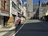 デュオメゾン西新宿 周辺商業施設が立ち並ぶ街路から見た建物外観
