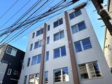 デュオメゾン西新宿 青空を背景に見た白と茶色の縦ラインが特徴的な建物外観