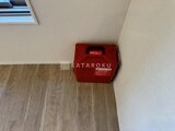 デュオメゾン西新宿 明るい床材と白壁のシンプルな室内に設置された赤い火災報知機