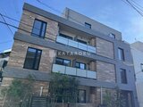 アンキ神宮前 木調タイルの外壁とガラスバルコニーが印象的なモダンな建物外観